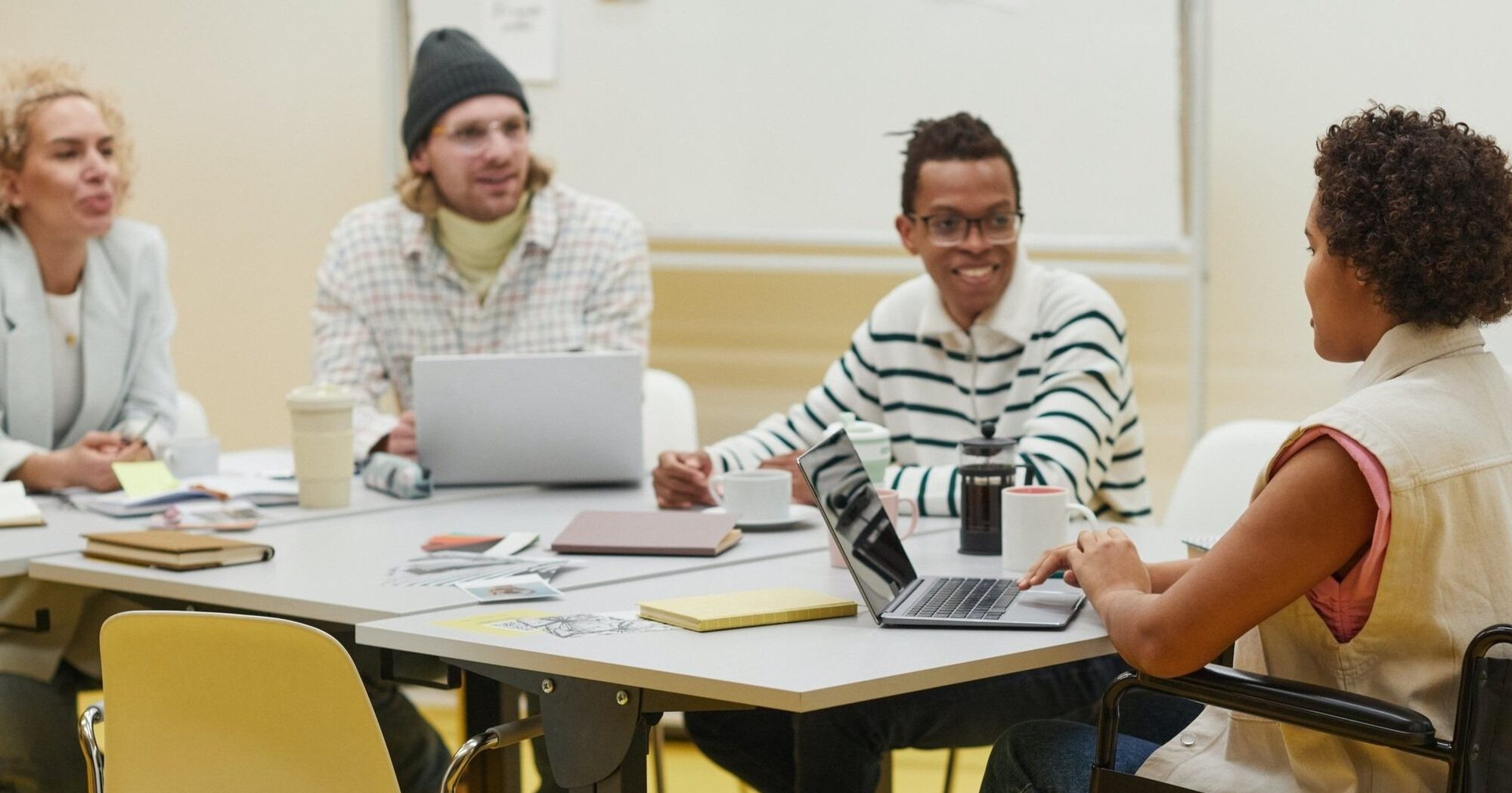 Diverse group of coworkers planning an event. From right to left: a blond white female, a blonde white male, a Black male with glasses, and a Black female seated in a wheelchair.